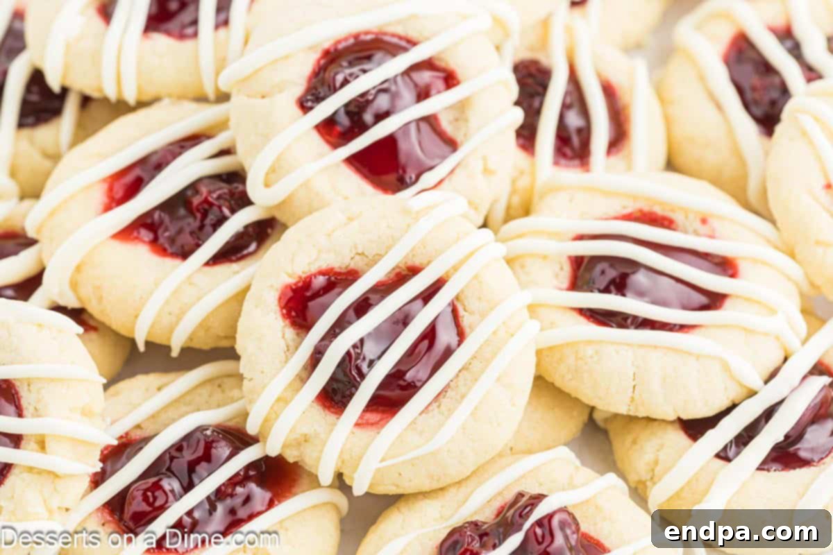 Crimson Cherry Thumbprint Cookies 2 A stack of golden-baked Cherry Thumbprint cookies, each with a bright red cherry filling and a delicate white chocolate drizzle.