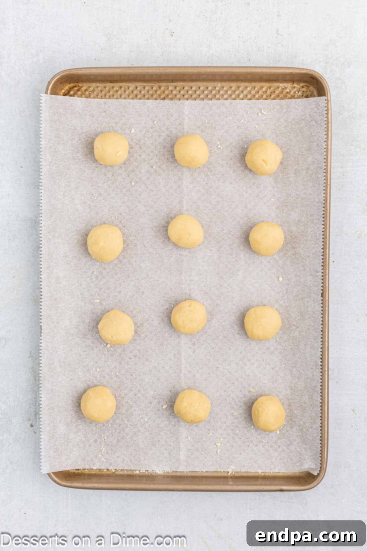 Crimson Cherry Thumbprint Cookies 6 Small, uniform balls of cookie dough arranged on a parchment-lined baking sheet, ready for baking.