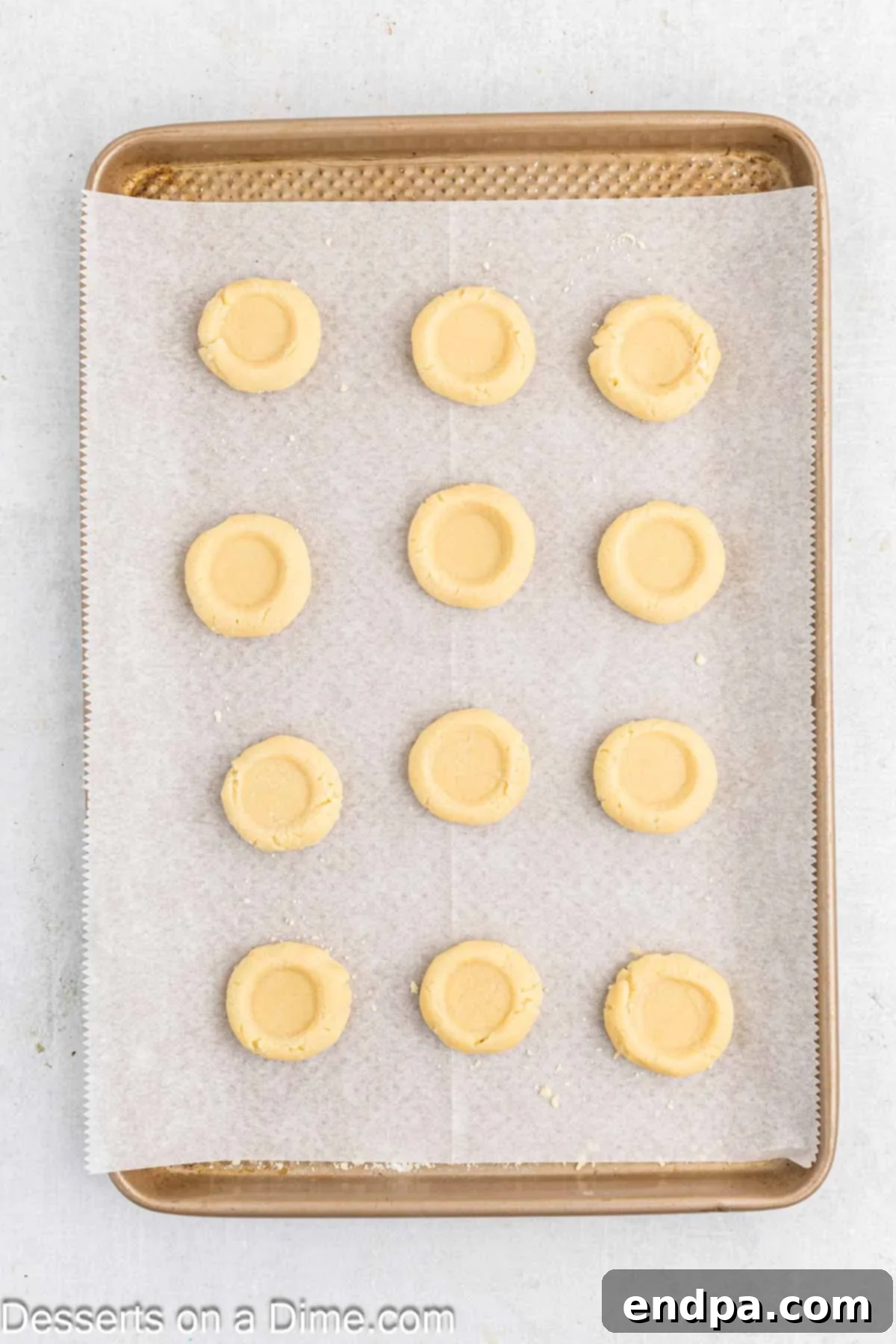 Crimson Cherry Thumbprint Cookies 7 A thumb pressed gently into the center of each cookie dough ball on a baking sheet, creating a clear indentation.