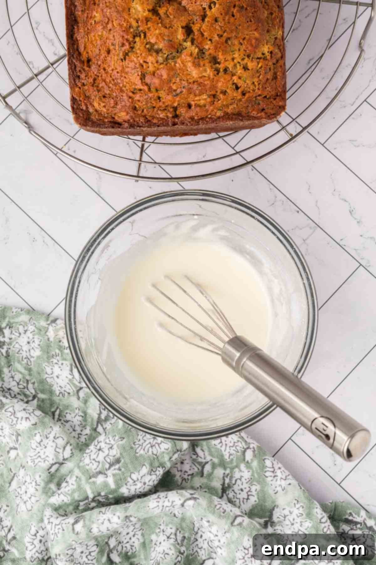A small bowl containing the smooth pineapple glaze, with a whisk resting in it.