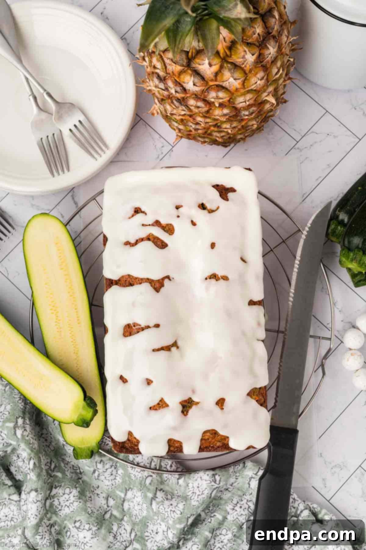 A beautiful loaf of Zucchini Bread with Pineapple, glistening with glaze on a rustic cutting board.