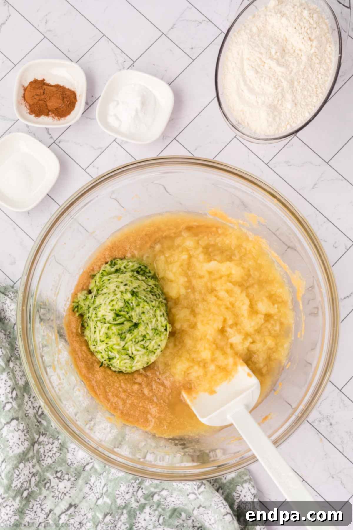 Grated zucchini and crushed pineapple being folded into the wet batter mixture.