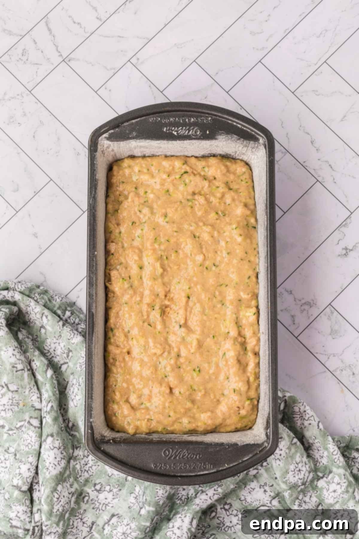 The zucchini pineapple bread batter neatly poured into a prepared loaf pan.