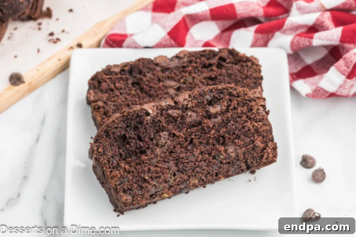 Slices of rich and moist Chocolate Zucchini Bread on a white plate, showcasing its delicious texture.