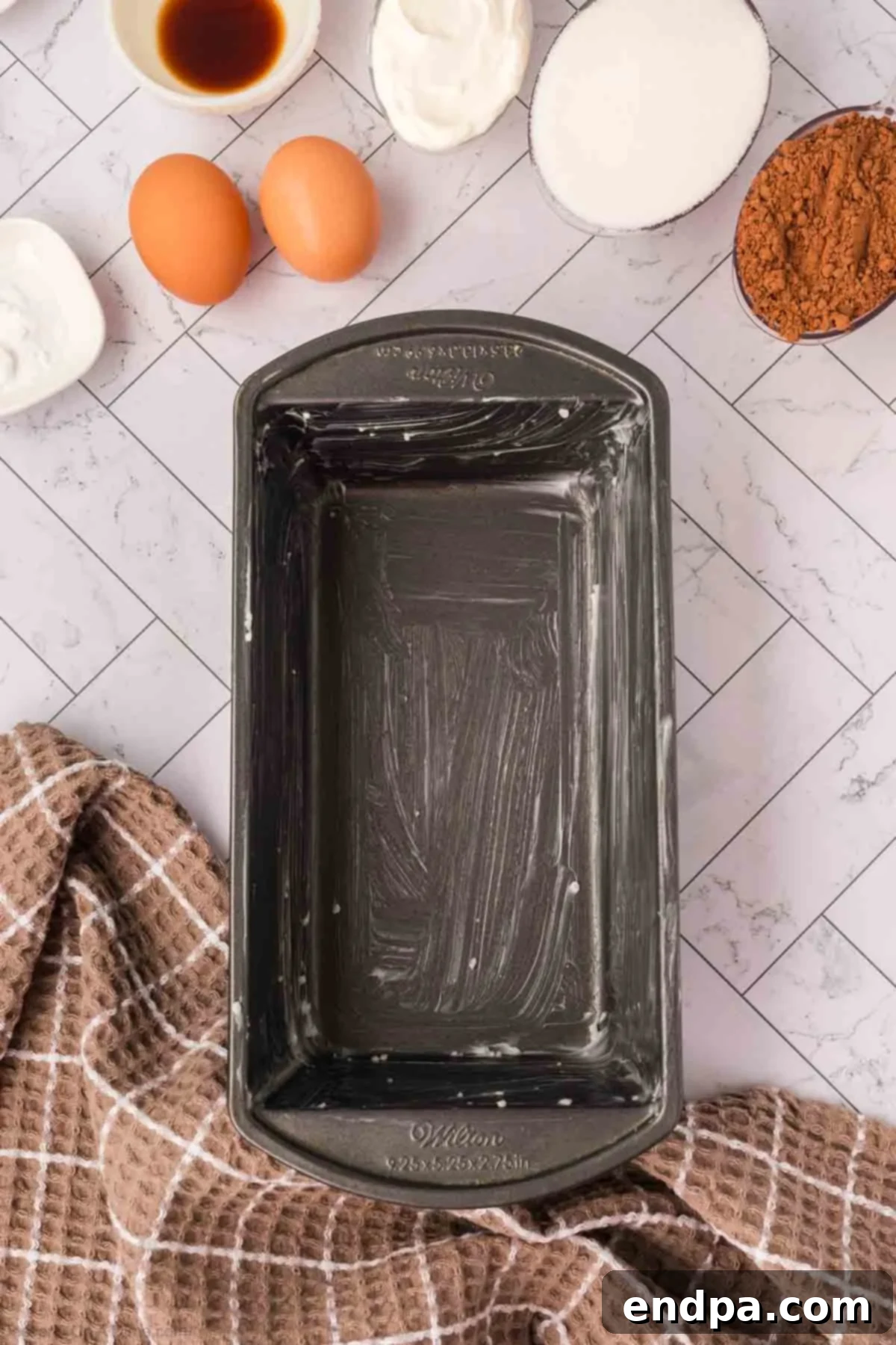 A loaf pan, greased and ready to use, prepared for the Chocolate Zucchini Bread batter.