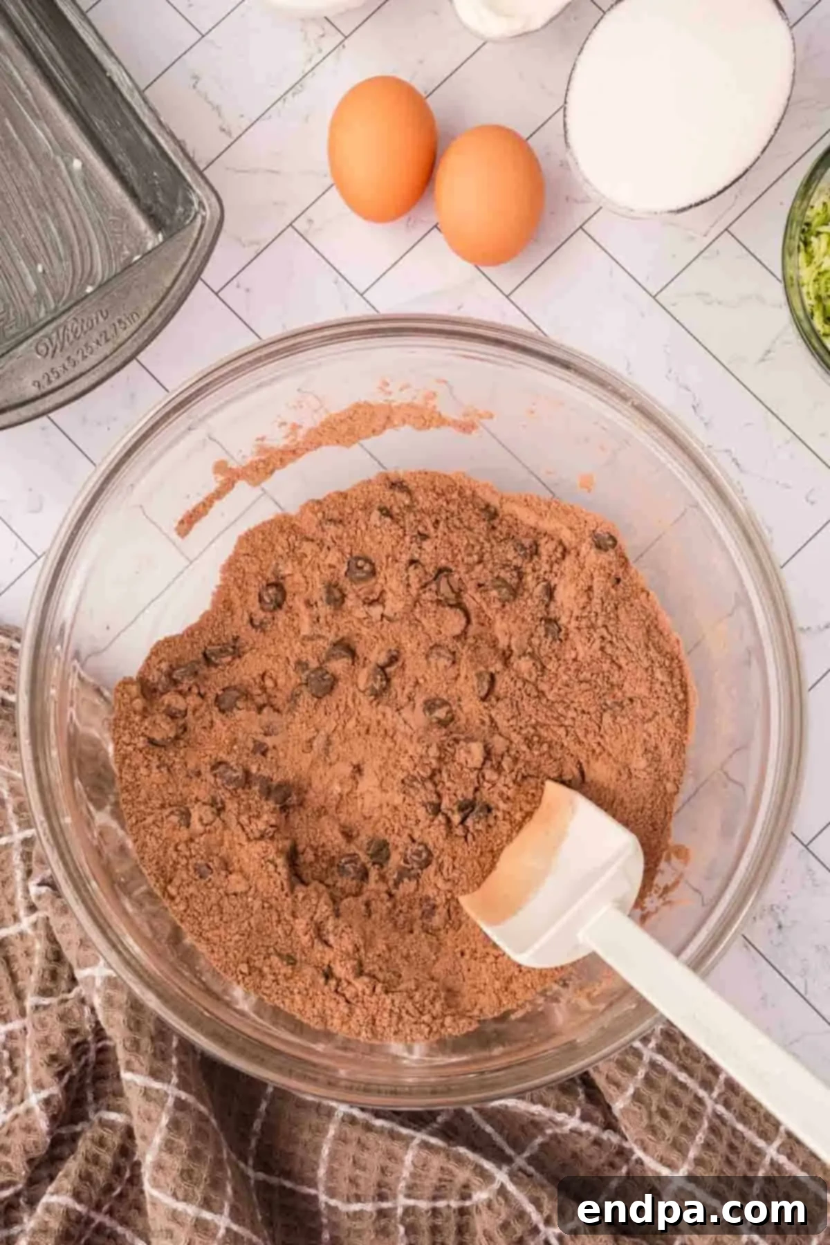 Chocolate chips being stirred into the dry ingredients in a mixing bowl.