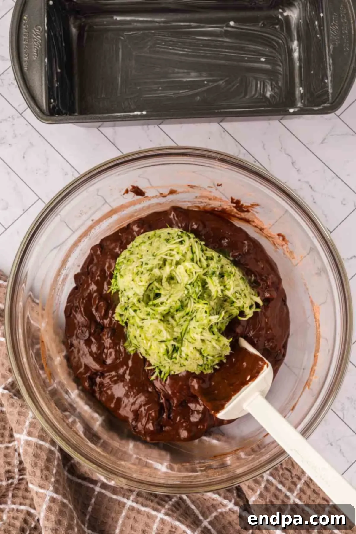 Shredded zucchini being folded into the chocolate batter.