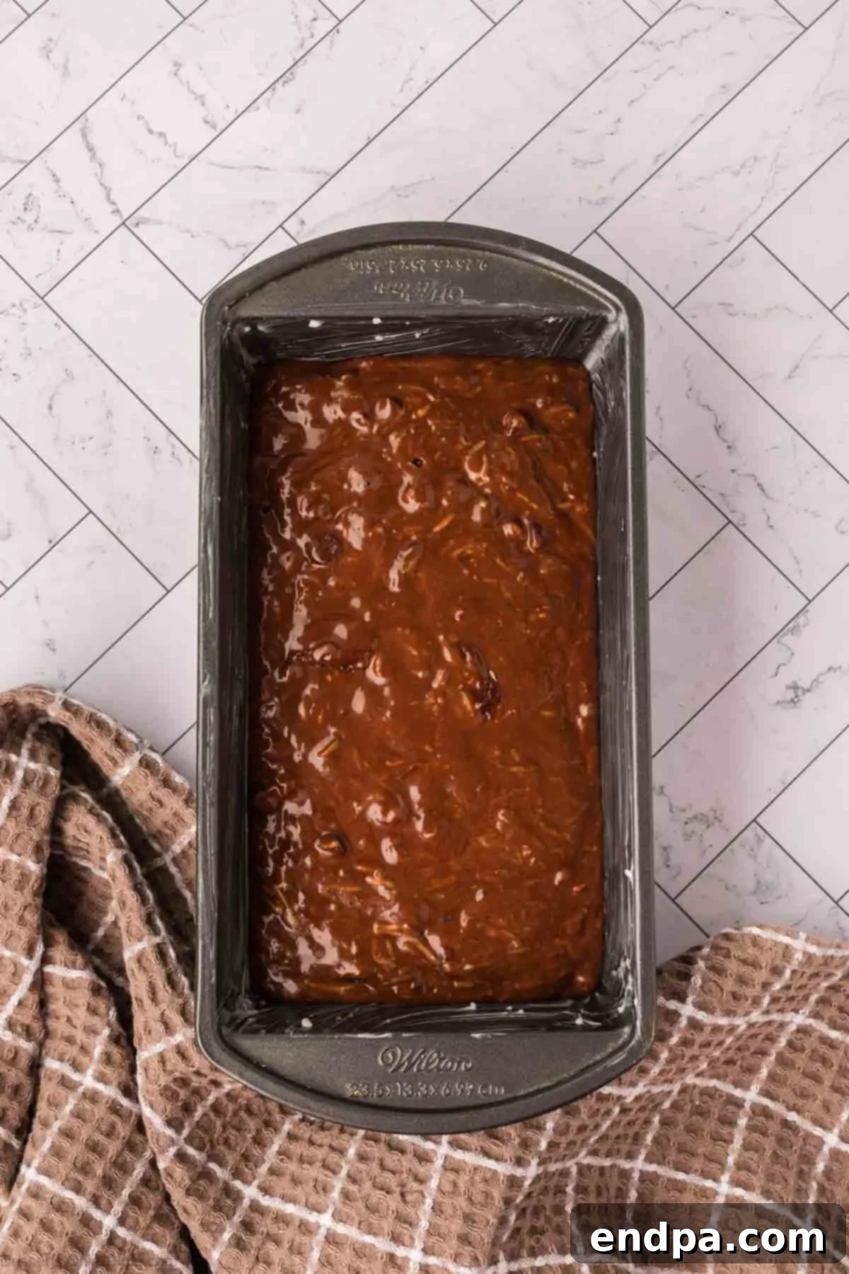 Chocolate Zucchini Bread batter spread evenly into a prepared loaf pan, ready for baking.