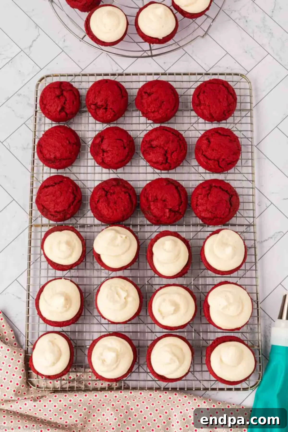 Cream cheese frosting piped onto half of the cooled red velvet cookies.