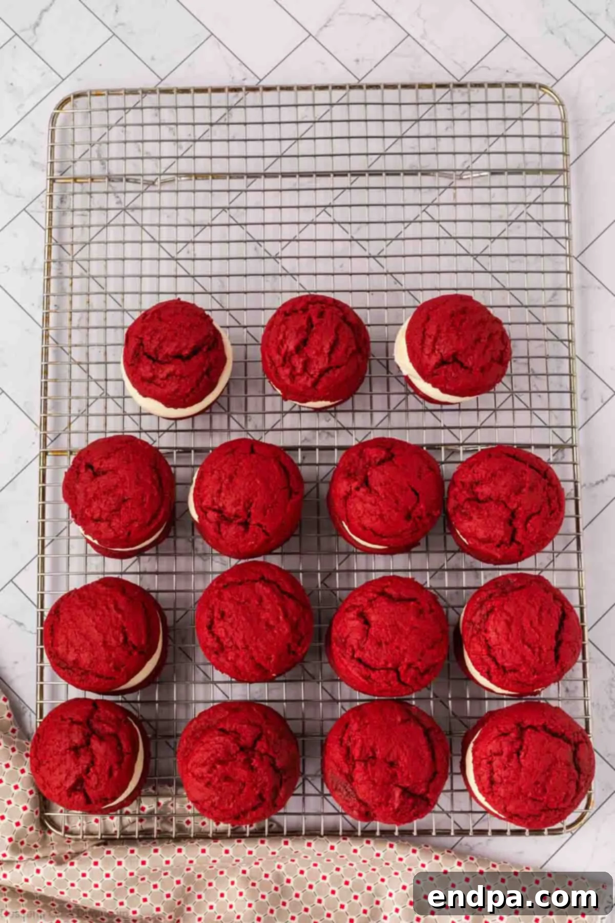 Second red velvet cookies placed on top of frosted cookies to create sandwich cookies.