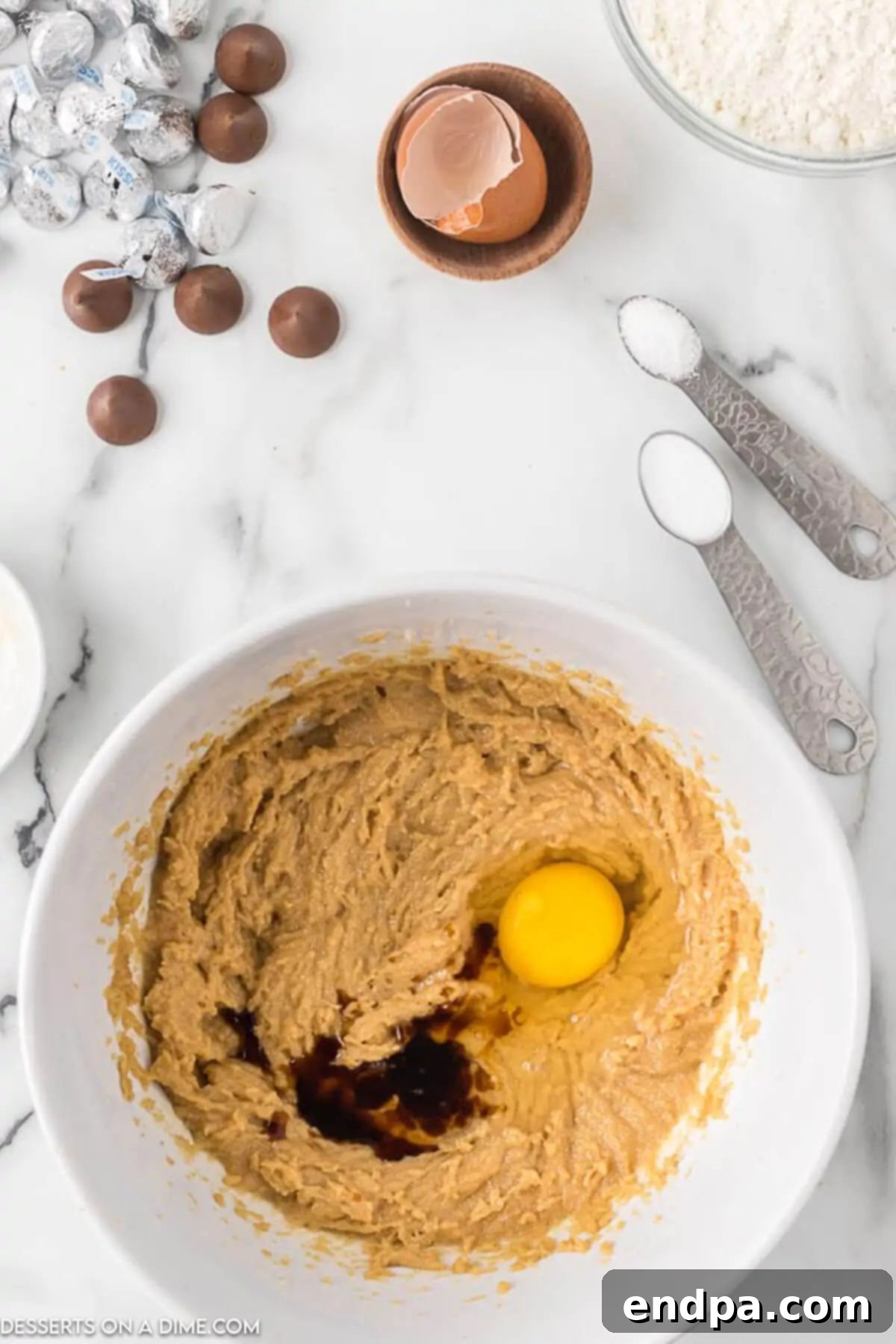 Adding a room temperature egg and pure vanilla extract to the creamed peanut butter mixture.
