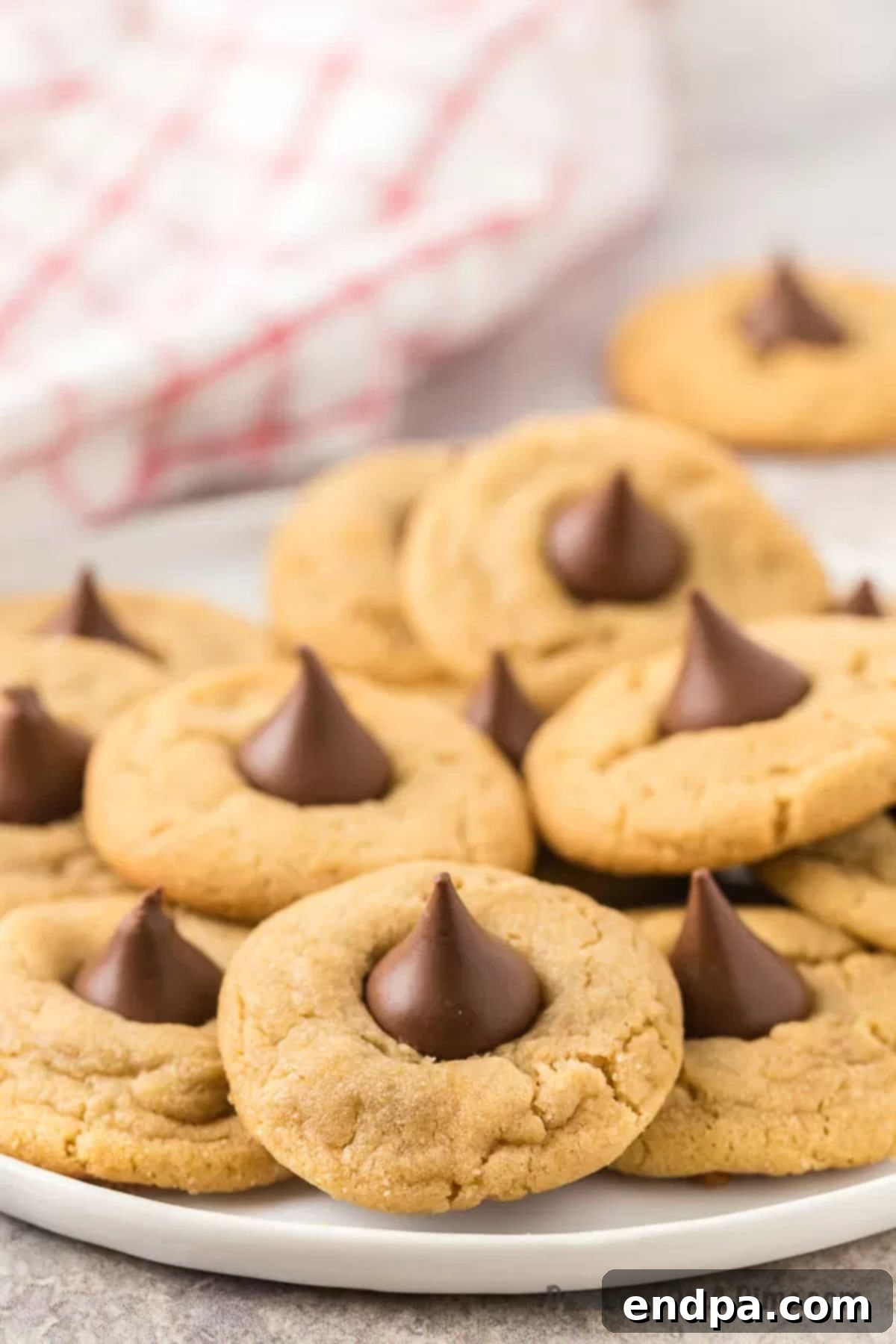 A charming plate of Peanut Butter Hershey Kiss Cookies, stacked enticingly and ready to serve.