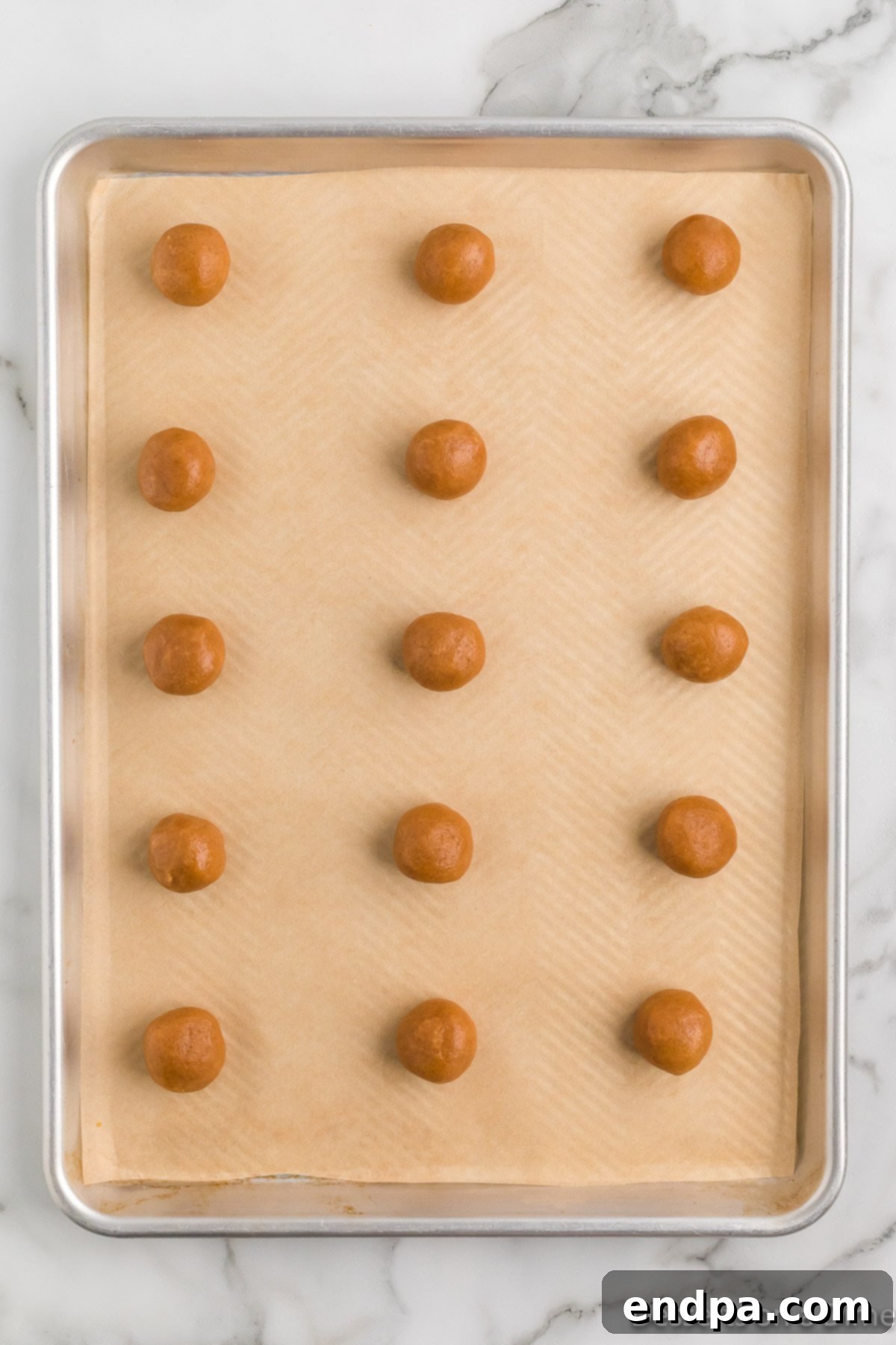 Decadent Keto Peanut Butter Cookies 5 Uniform dough balls of Keto Peanut Butter Cookies neatly arranged on a baking sheet lined with parchment paper.