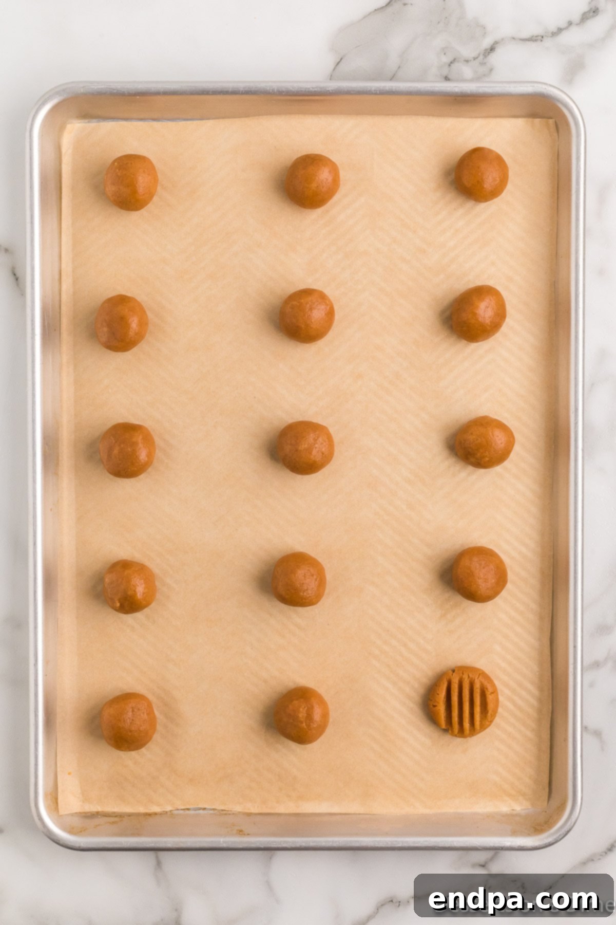 Decadent Keto Peanut Butter Cookies 6 Unbaked Keto Peanut Butter Cookie dough balls with the classic criss-cross fork pattern pressed into their tops.