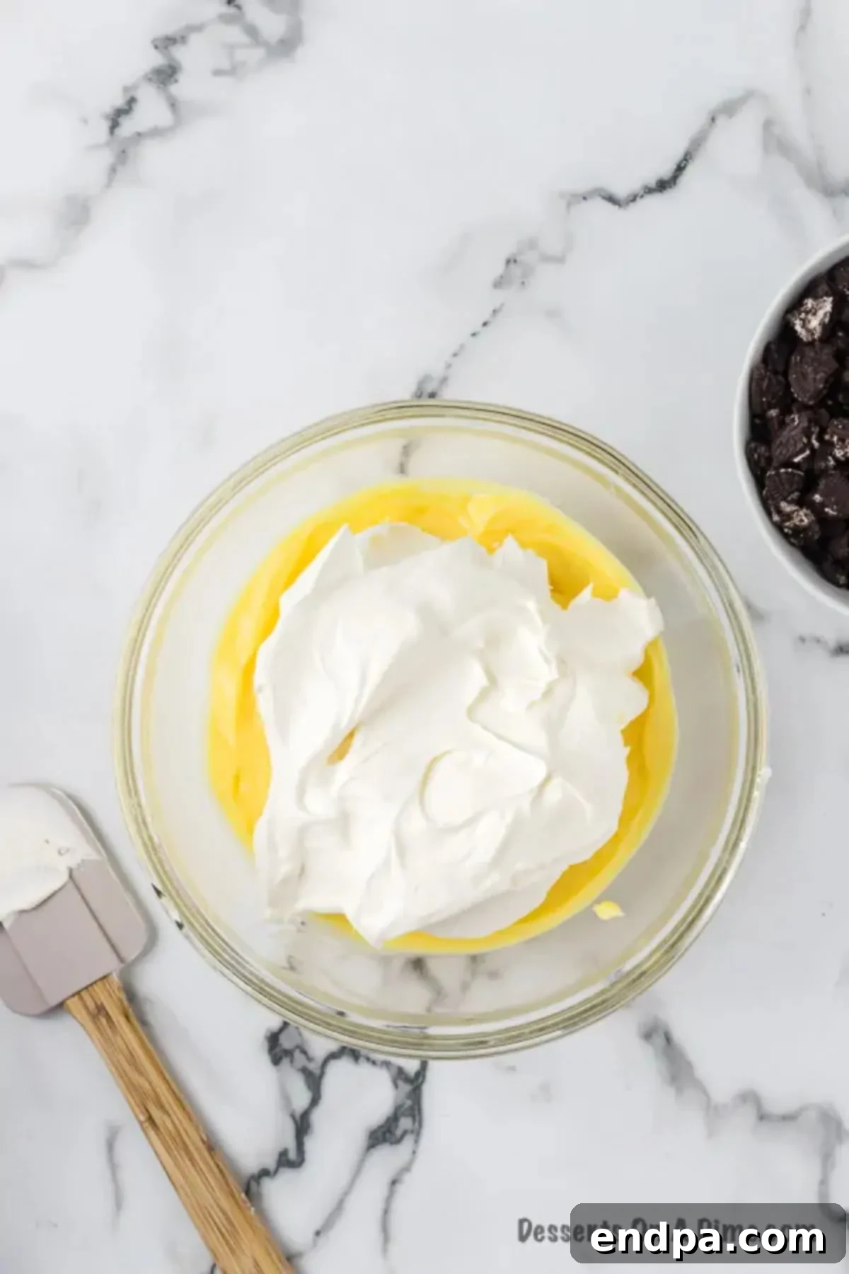 Whipped cream folded into bowl with pudding.