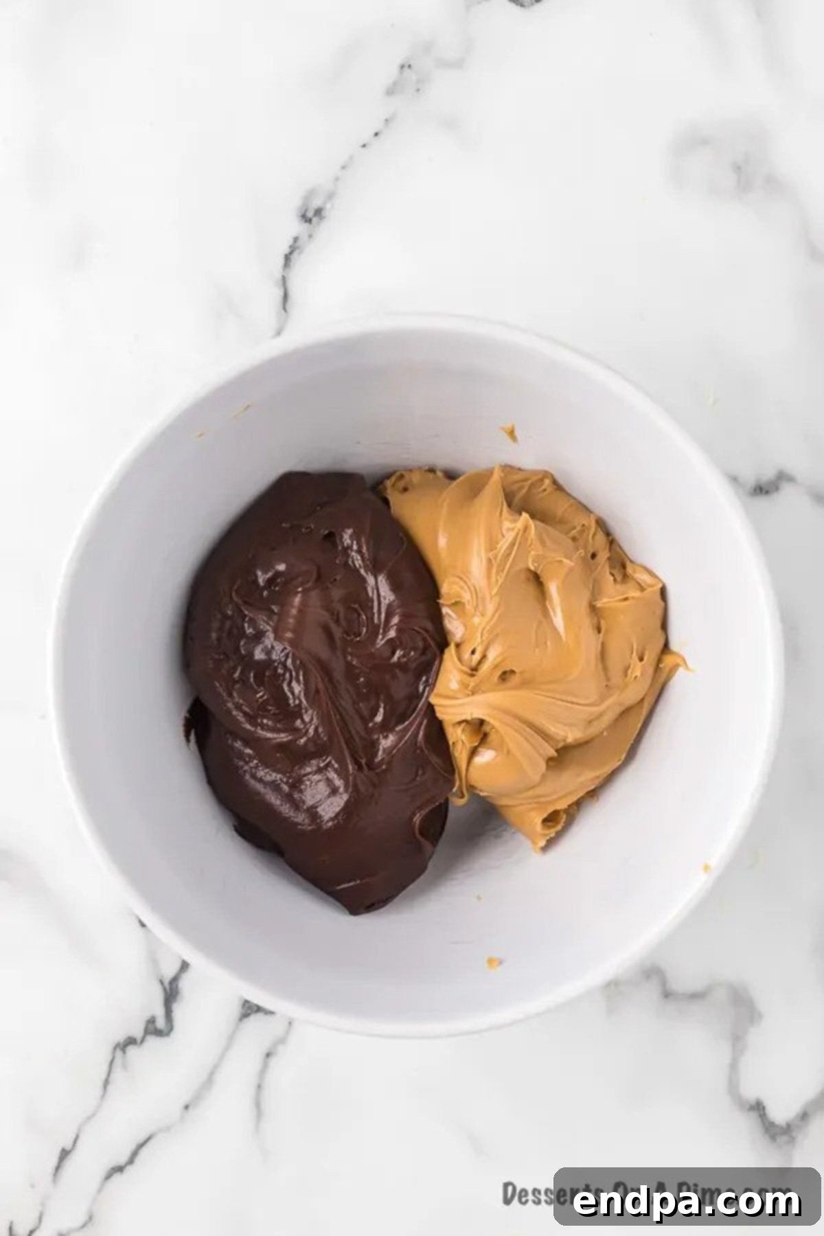 A microwave-safe bowl containing creamy peanut butter and rich chocolate frosting, ready to be melted.