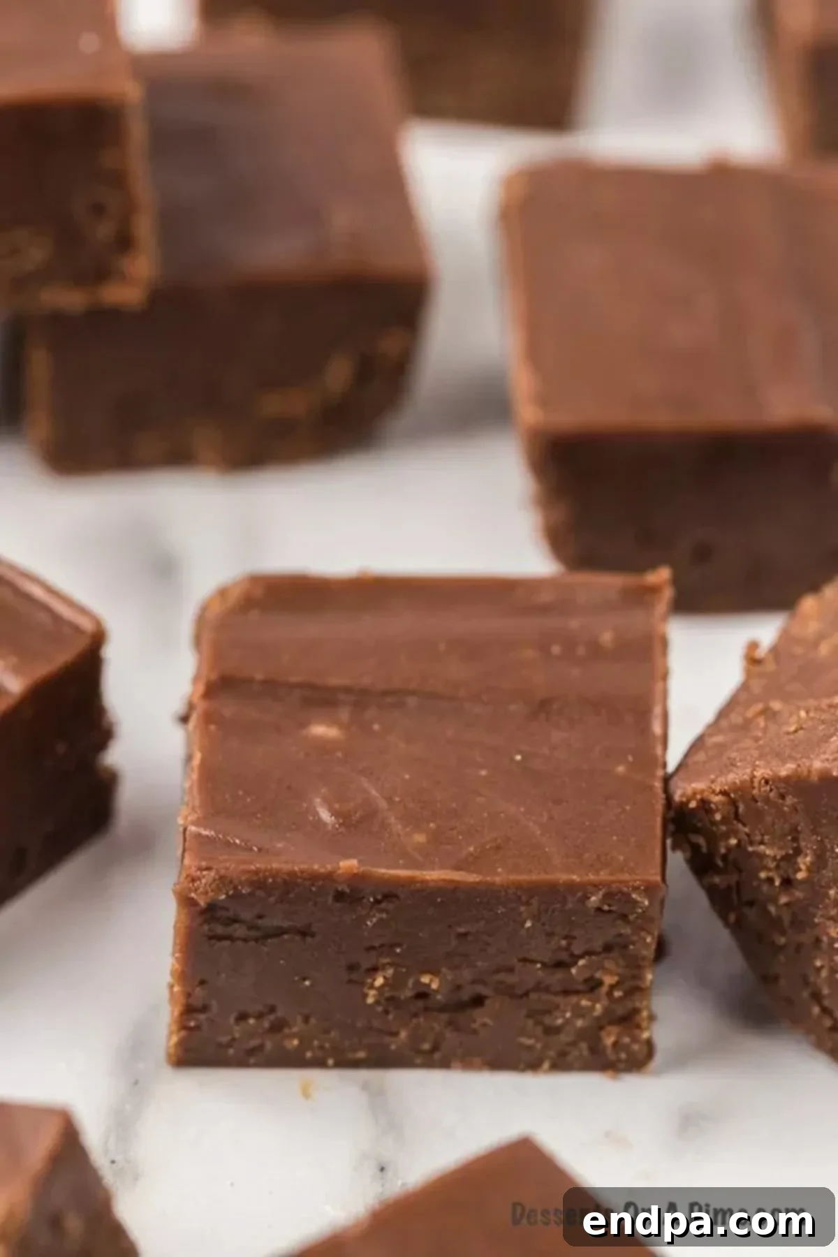 An array of perfectly square chocolate peanut butter fudge pieces, showcasing their rich, smooth texture.