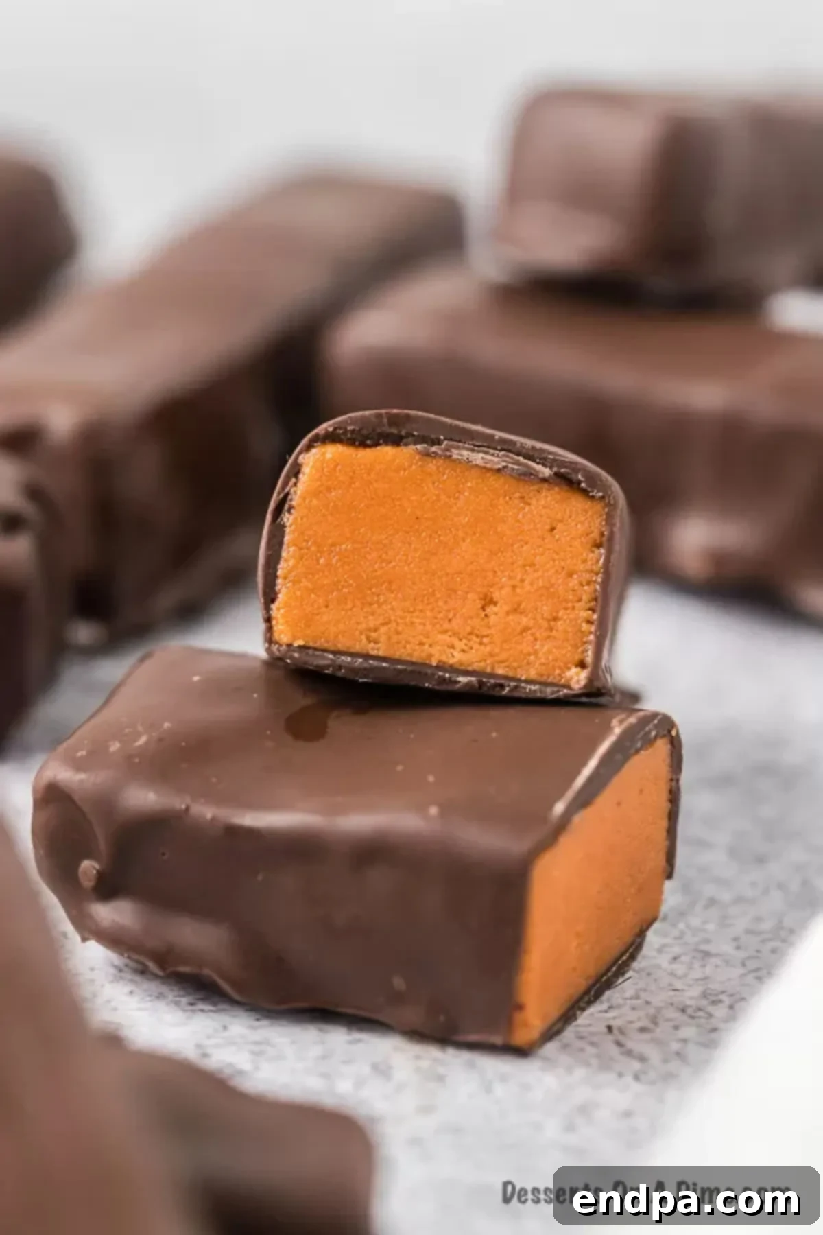 DIY Butterfinger Bliss 2 Close up picture of homemade Butterfinger cut in half, showcasing the flaky, crunchy peanut butter core and glistening chocolate coating.