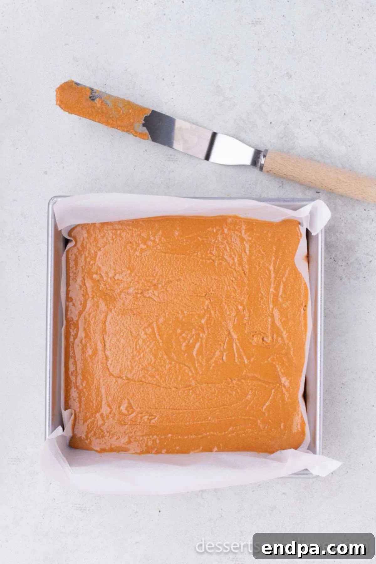 DIY Butterfinger Bliss 5 The peanut butter and candy corn mixture evenly spread into the prepared 8x8 baking dish, ready to set.