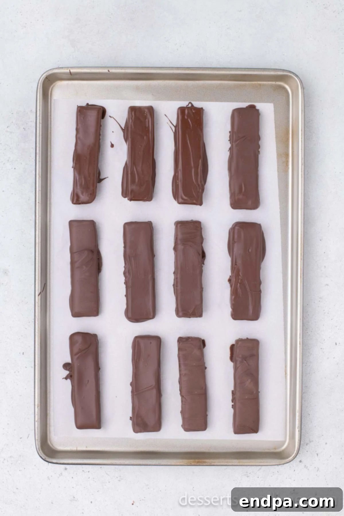 DIY Butterfinger Bliss 7 Finished homemade Butterfinger bars coated in glossy chocolate and resting on a parchment-lined baking sheet to set.