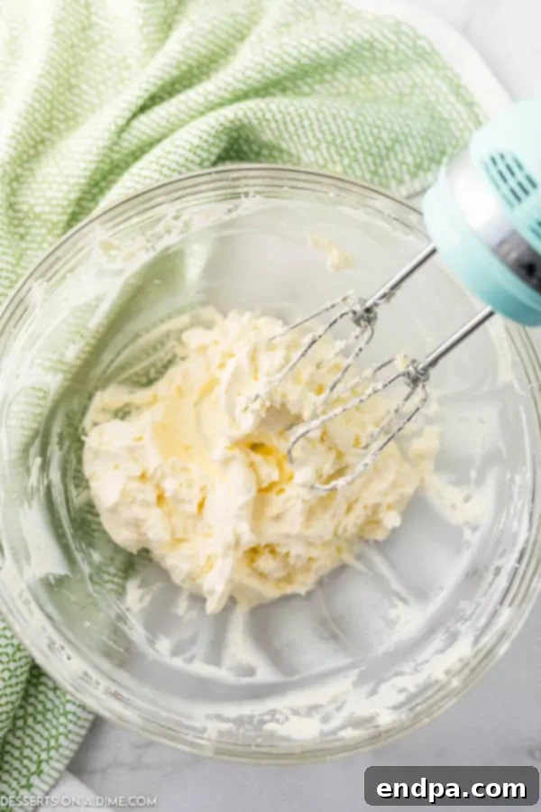 Softened cream cheese and butter combined in a mixing bowl, being creamed together.