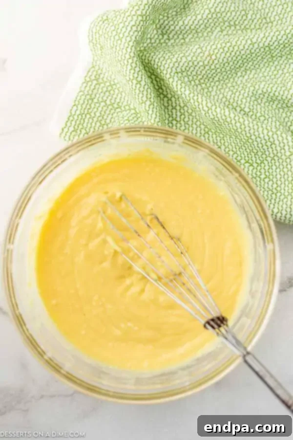 Milk and vanilla instant pudding mix being whisked together in a separate bowl.