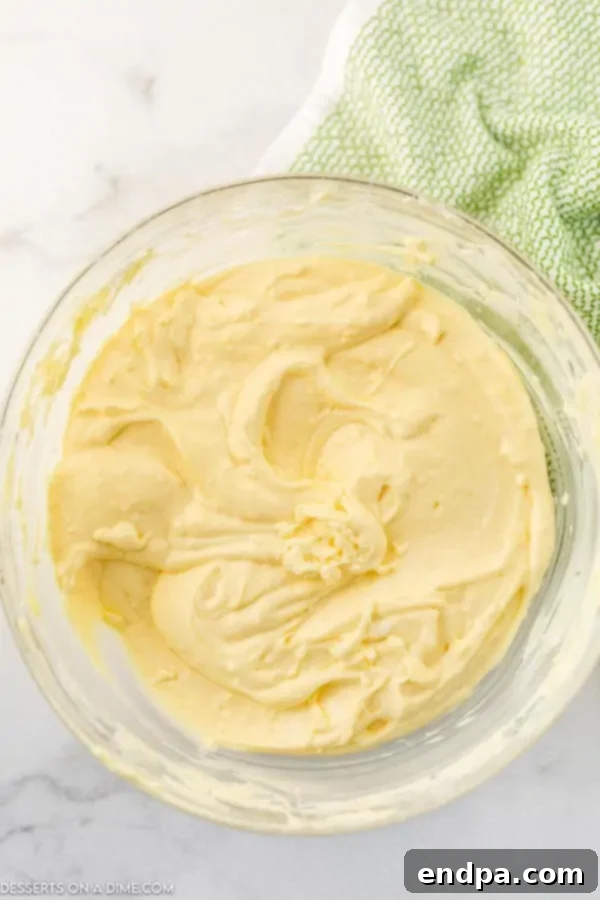 Thickened pudding mixture being gently folded into the cream cheese mixture.