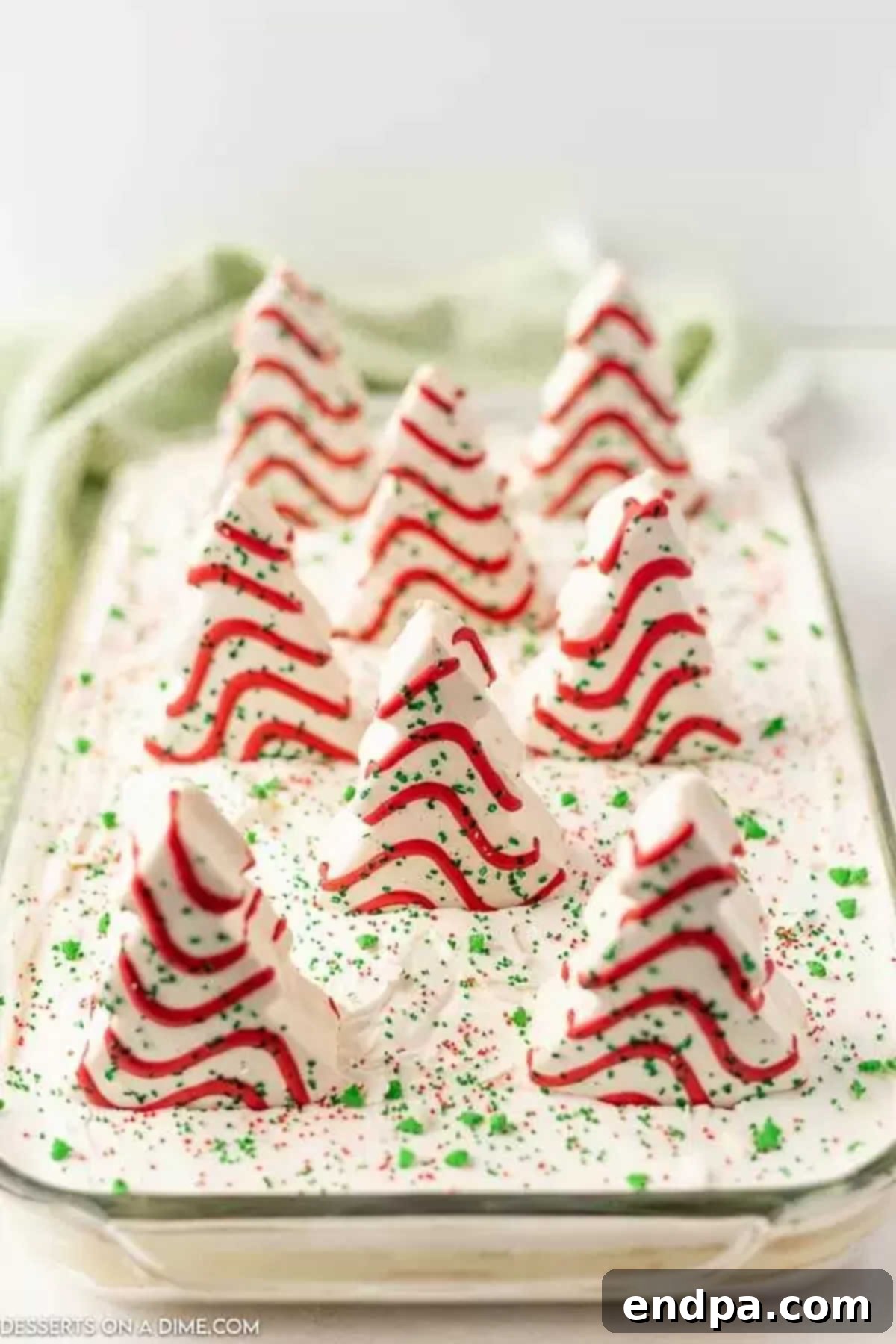 Little Debbie Christmas Tree Cakes and green sprinkles arranged on top of the chilled Christmas dirt cake.