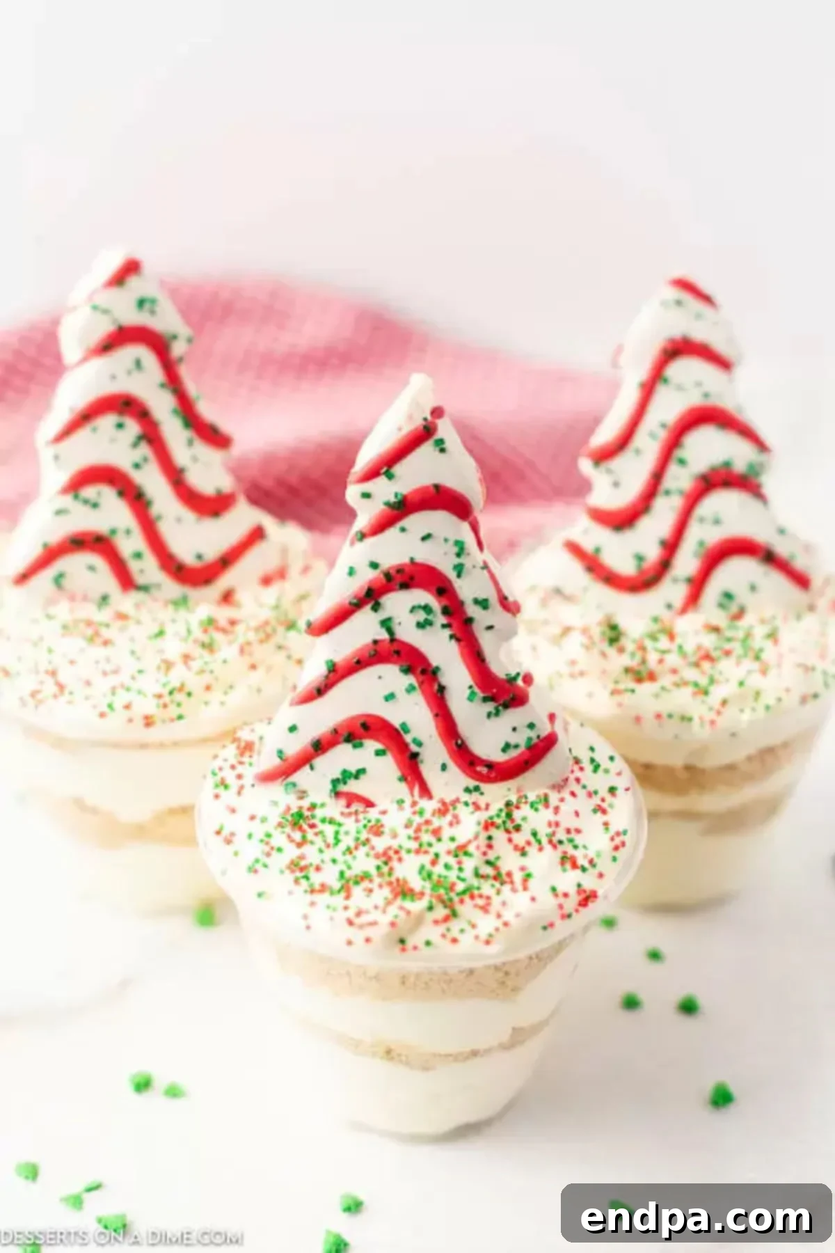Festive Christmas dirt cups topped with a Little Debbie Christmas tree cake.