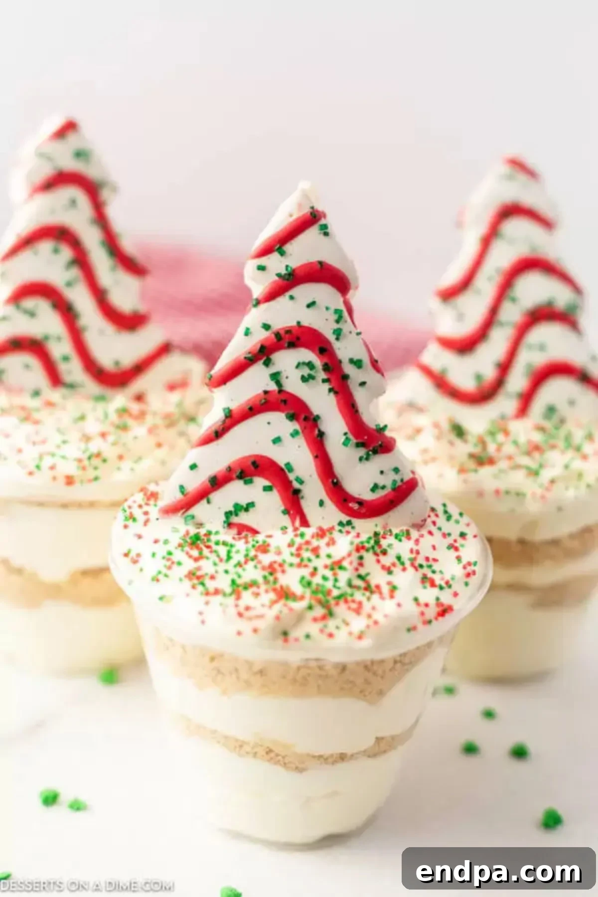 Assembled Christmas dirt cups topped with a Little Debbie Christmas tree and sprinkles.