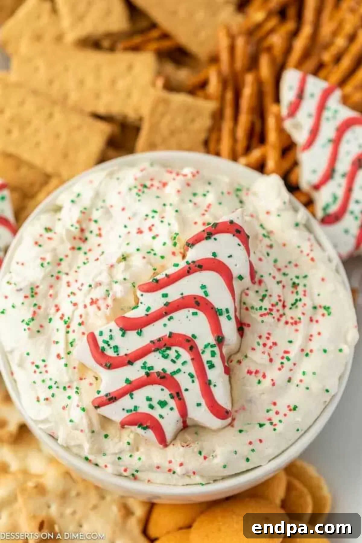 A beautifully presented bowl of Little Debbie Christmas Tree Dip, garnished with festive sprinkles and a whole Little Debbie Christmas Tree Cake, surrounded by a variety of dippers.