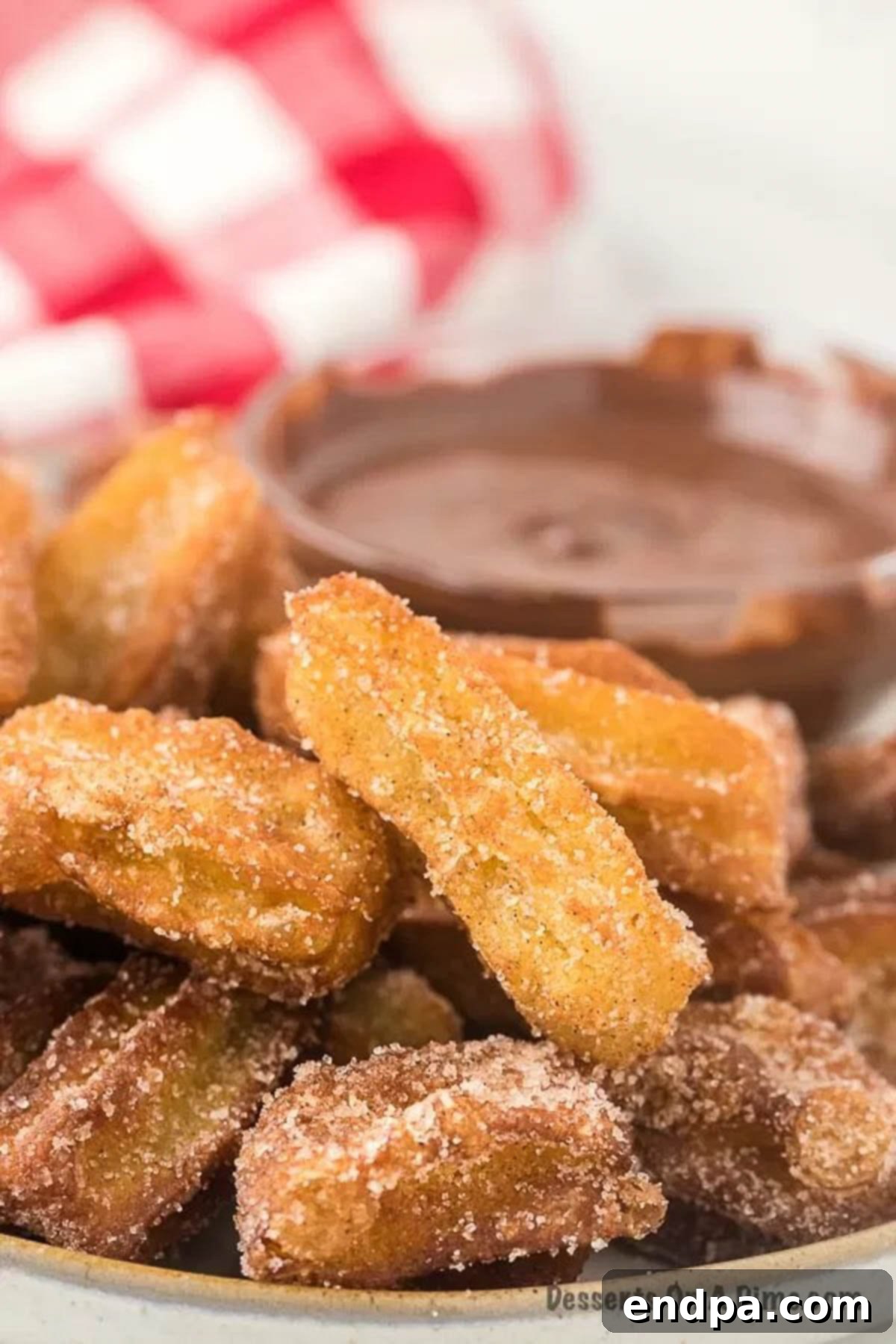 Churros on a platter beside chocolate sauce.