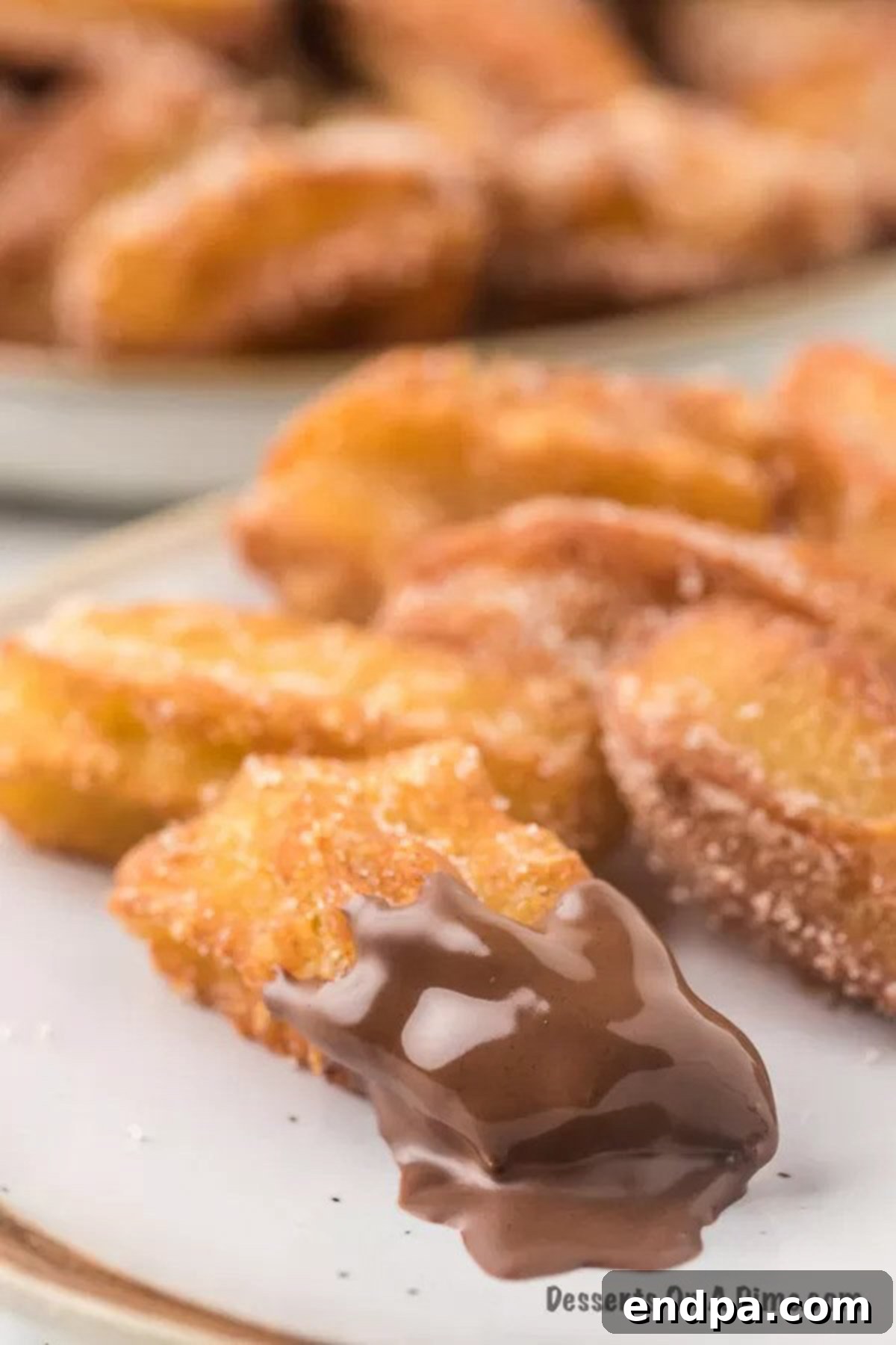 Churros on a plate with one dipped in  chocolate sauce.