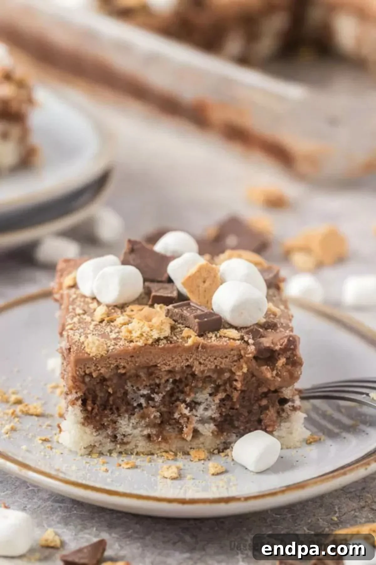 Campfire Delight Cake 2 A delectable slice of S'mores Poke Cake on a plate, showcasing its layers of chocolate, marshmallow, and graham cracker toppings.