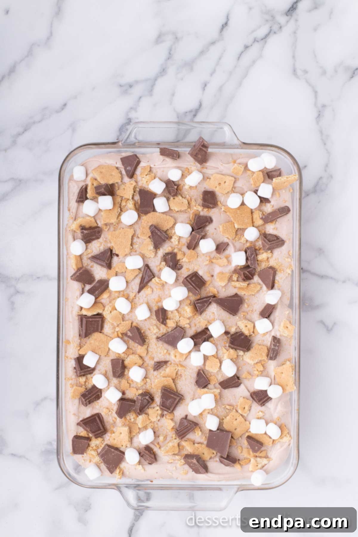 Campfire Delight Cake 11 The S'mores Poke Cake adorned with crushed graham crackers and chocolate pieces, awaiting its final marshmallow topping.