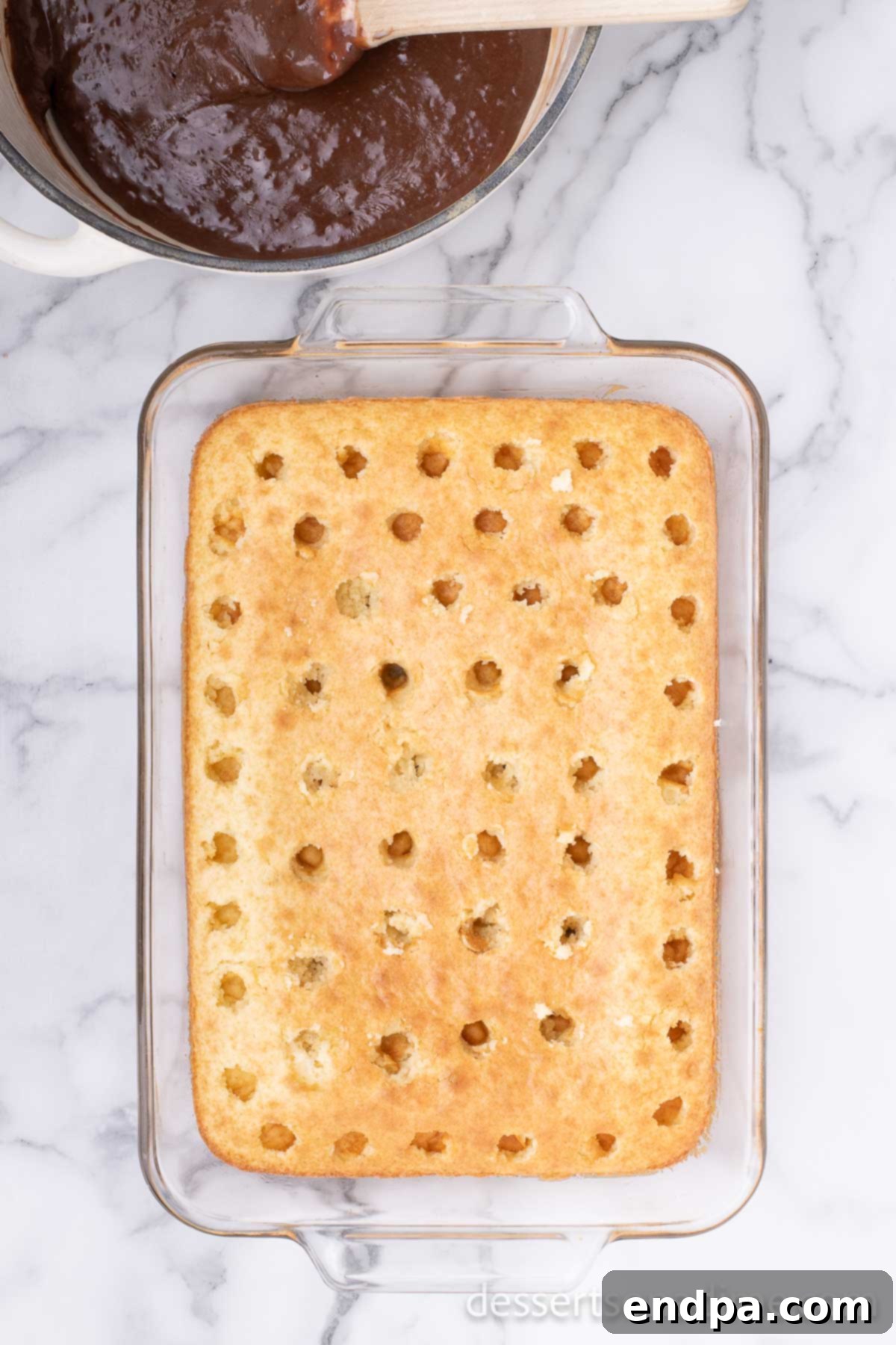 Campfire Delight Cake 4 A baked cake with numerous holes poked into its surface, prepared to absorb the delicious S'mores filling.