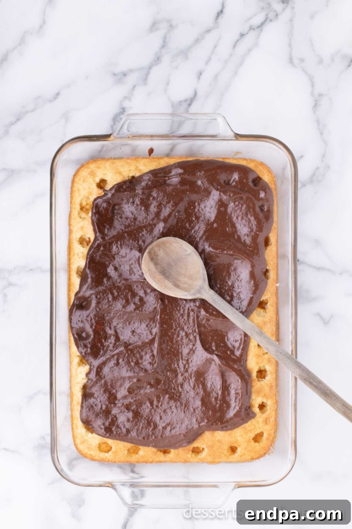 Campfire Delight Cake 7 The rich chocolate-marshmallow filling being spread evenly over the poked cake, ensuring it seeps into every hole.