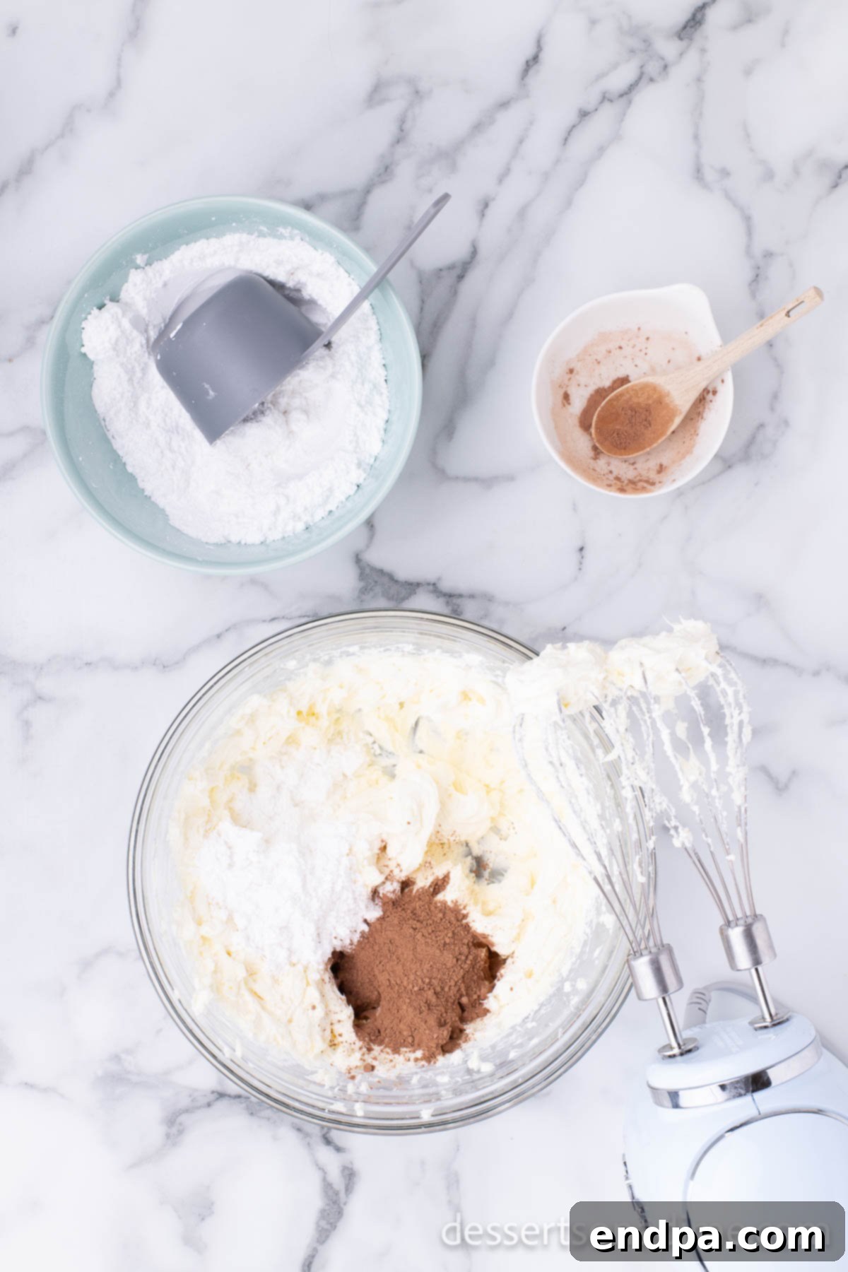 Campfire Delight Cake 8 A creamy, light brown mixture of cream cheese, powdered sugar, and cocoa powder blended smoothly in a mixing bowl.