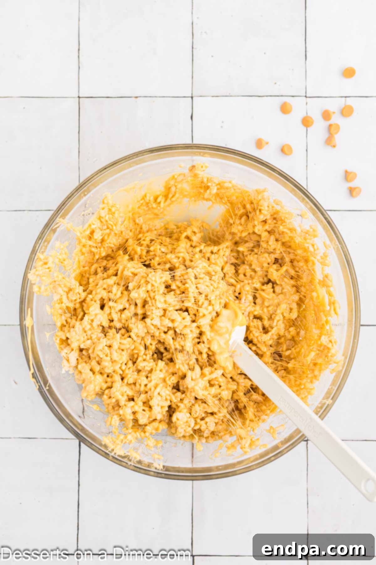 Rice Krispies cereal being coated with the melted marshmallow and butterscotch mixture in a large bowl.