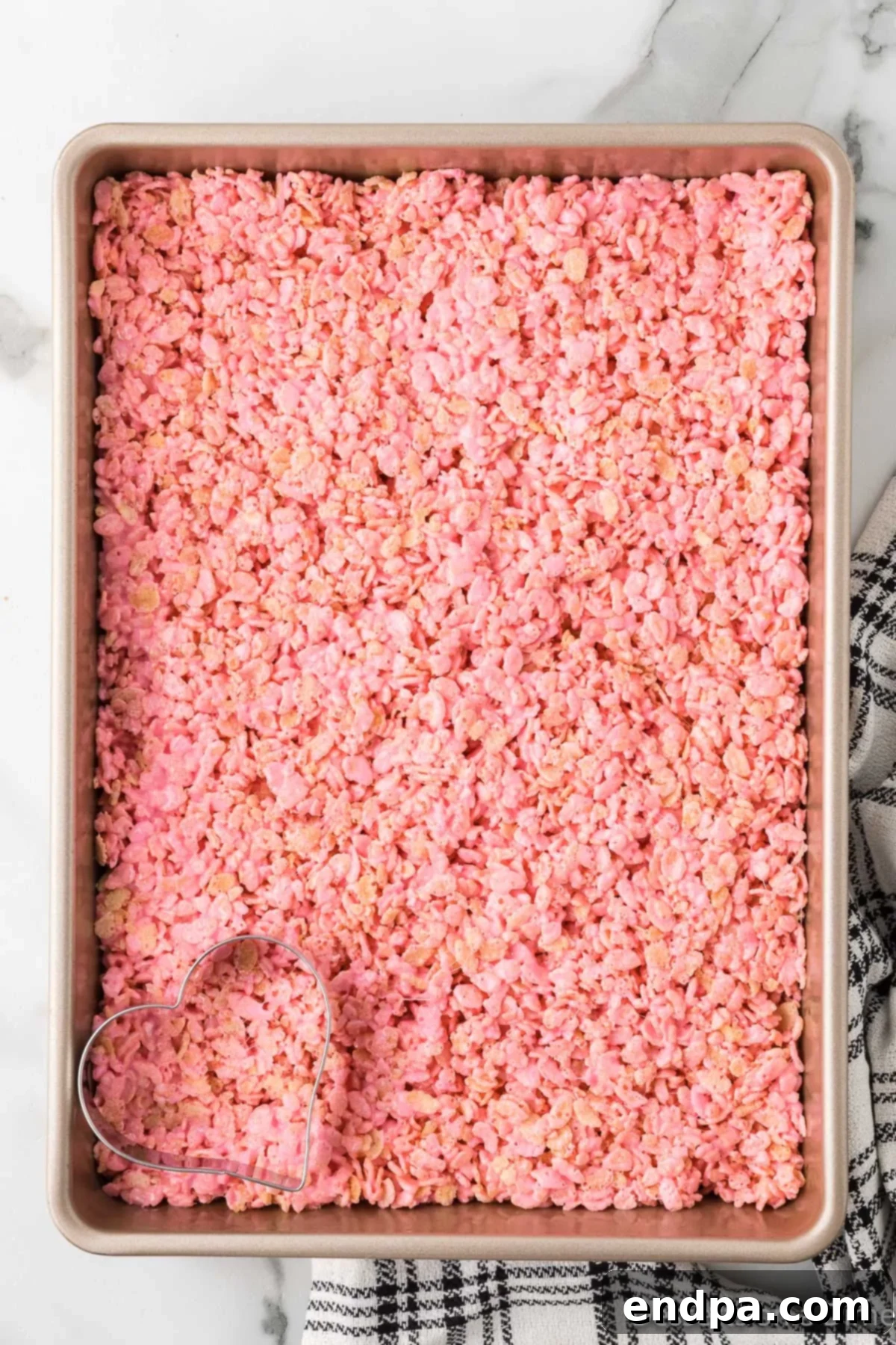 Sweetheart Crispy Treats 7 Cereal mixture spread into pan. The pink Rice Krispie mixture evenly pressed into a baking pan.