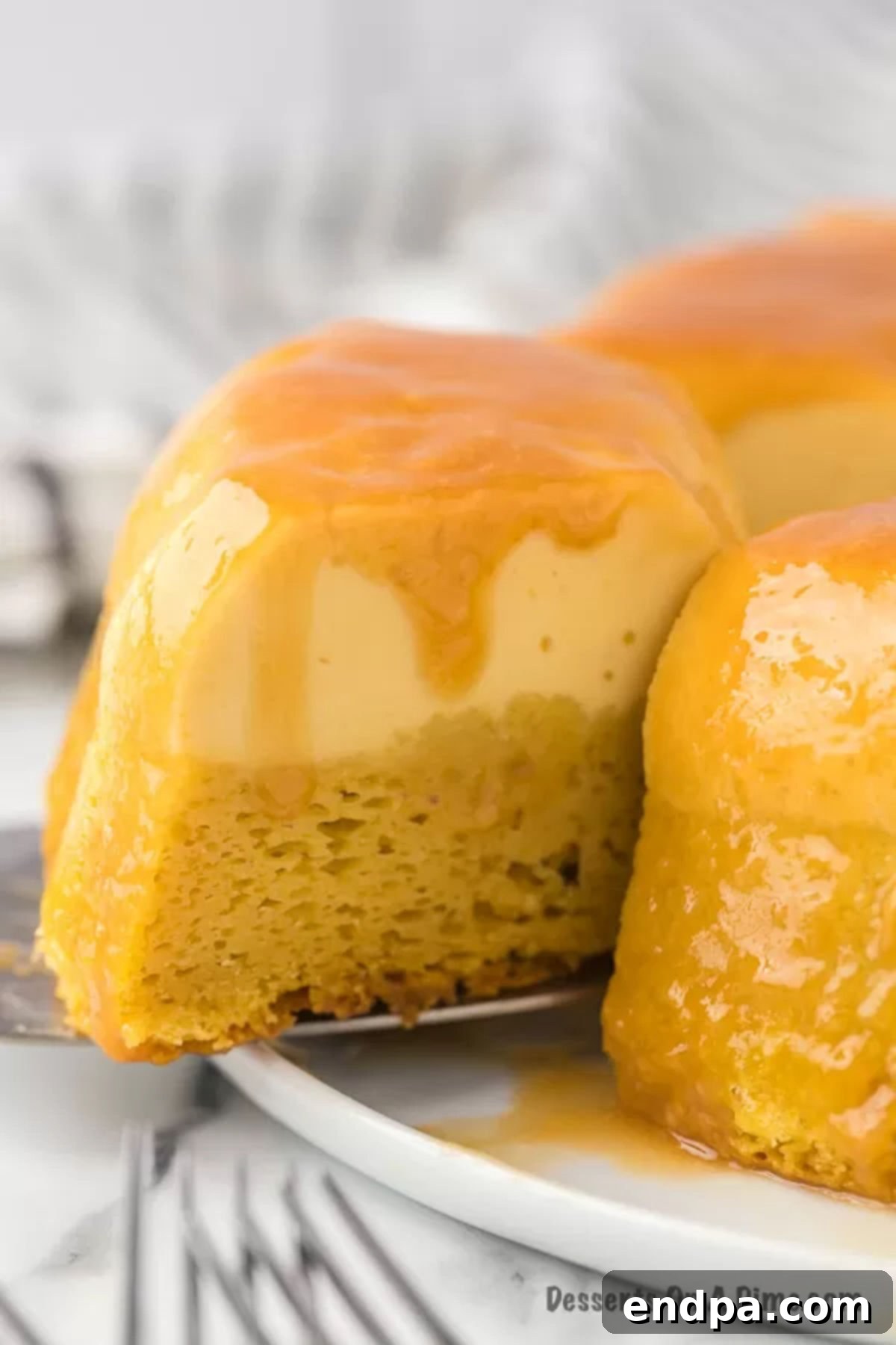 Flan cake on a serving platter with a slice removed, showing the cake and flan layers.