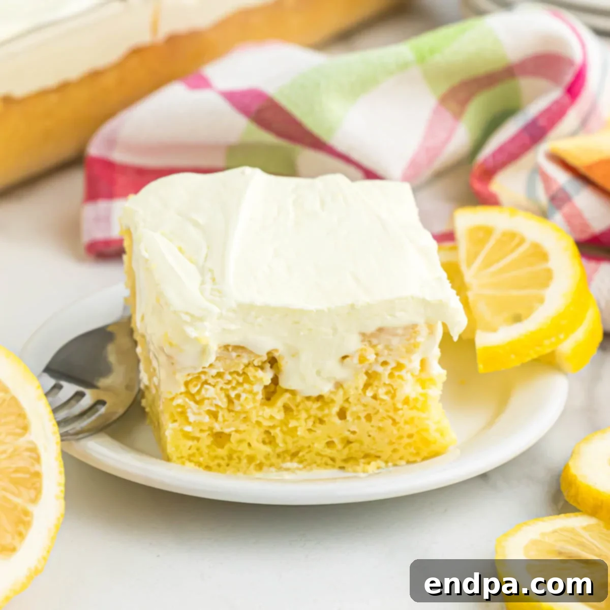Slice of lemon poke cake on a plate.