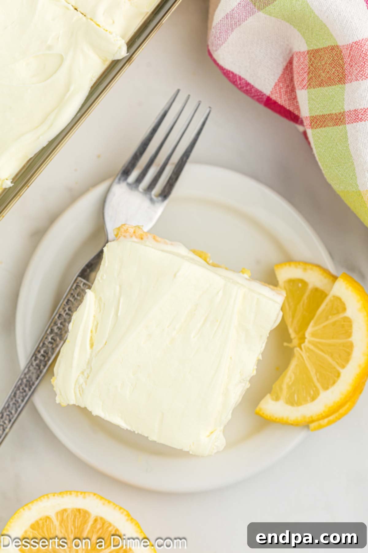 A beautifully frosted lemon poke cake, ready to be served, topped with a few lemon slices.