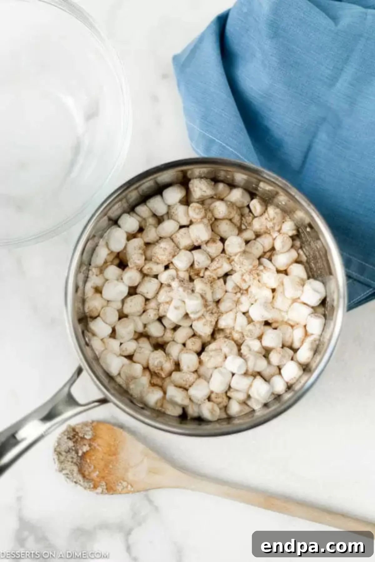 Mini marshmallows being stirred into the hot brown butter mixture in a saucepan.