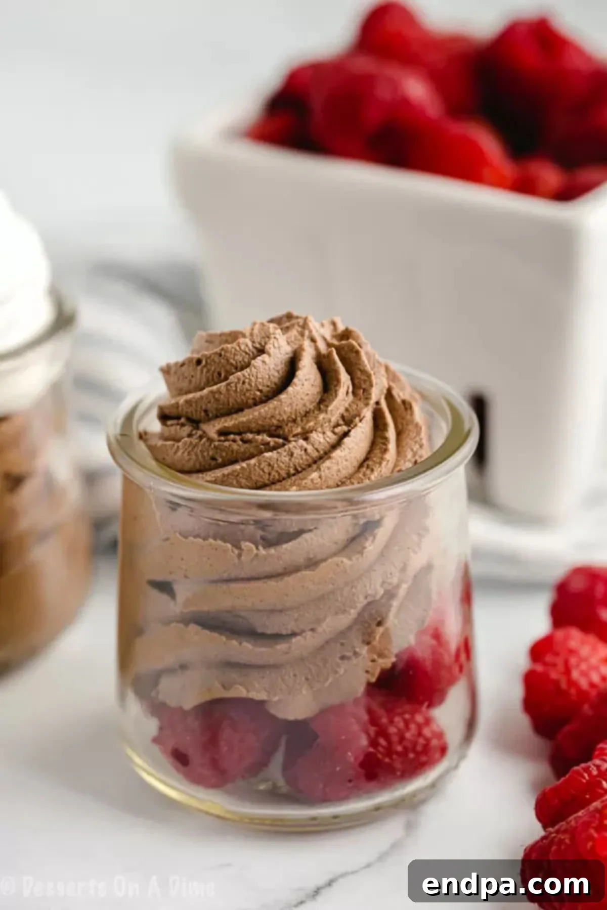 Keto Chocolate Mousse piped on top of fresh raspberries.