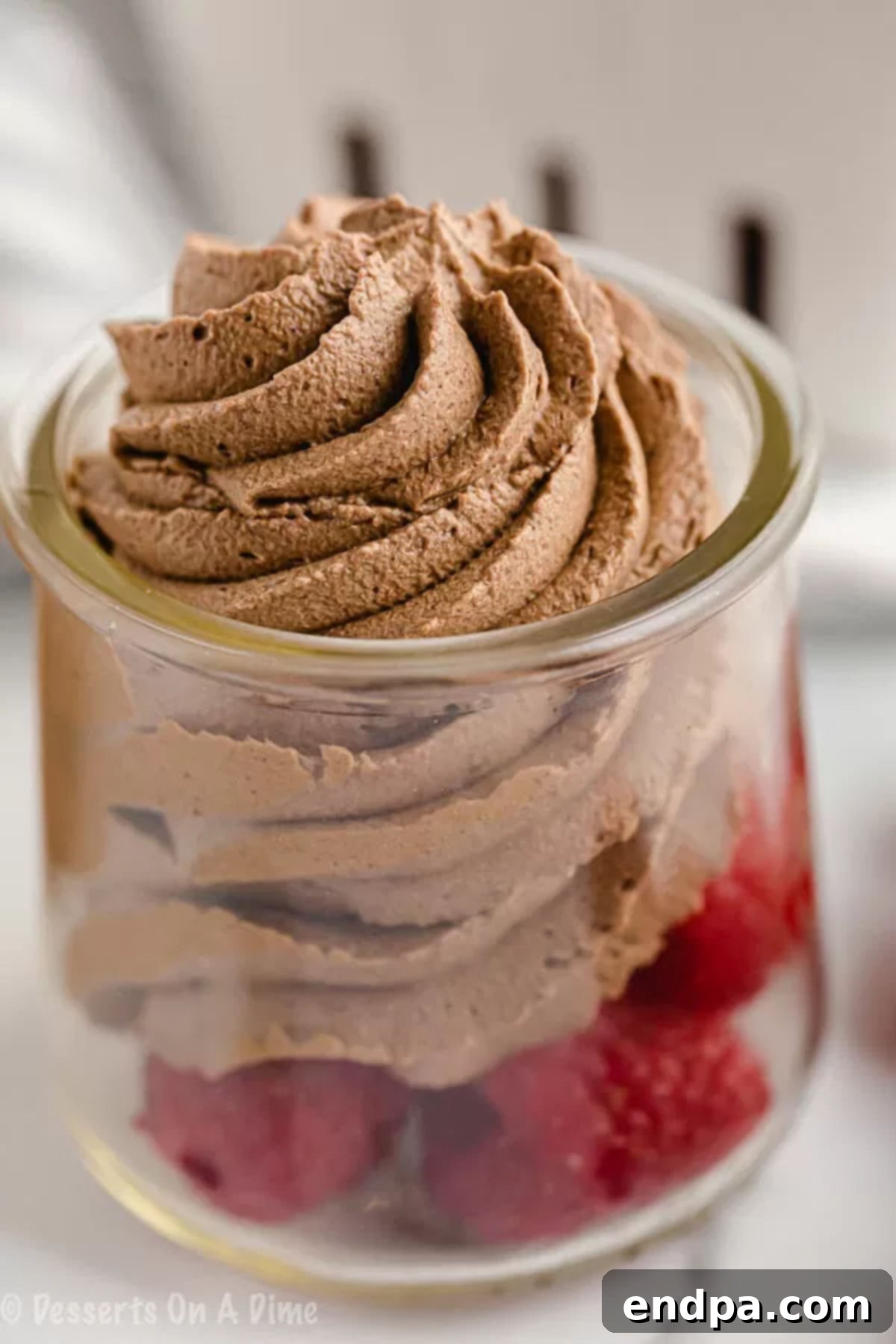 Close up of Keto Chocolate Mousse piped on top of fresh raspberries.