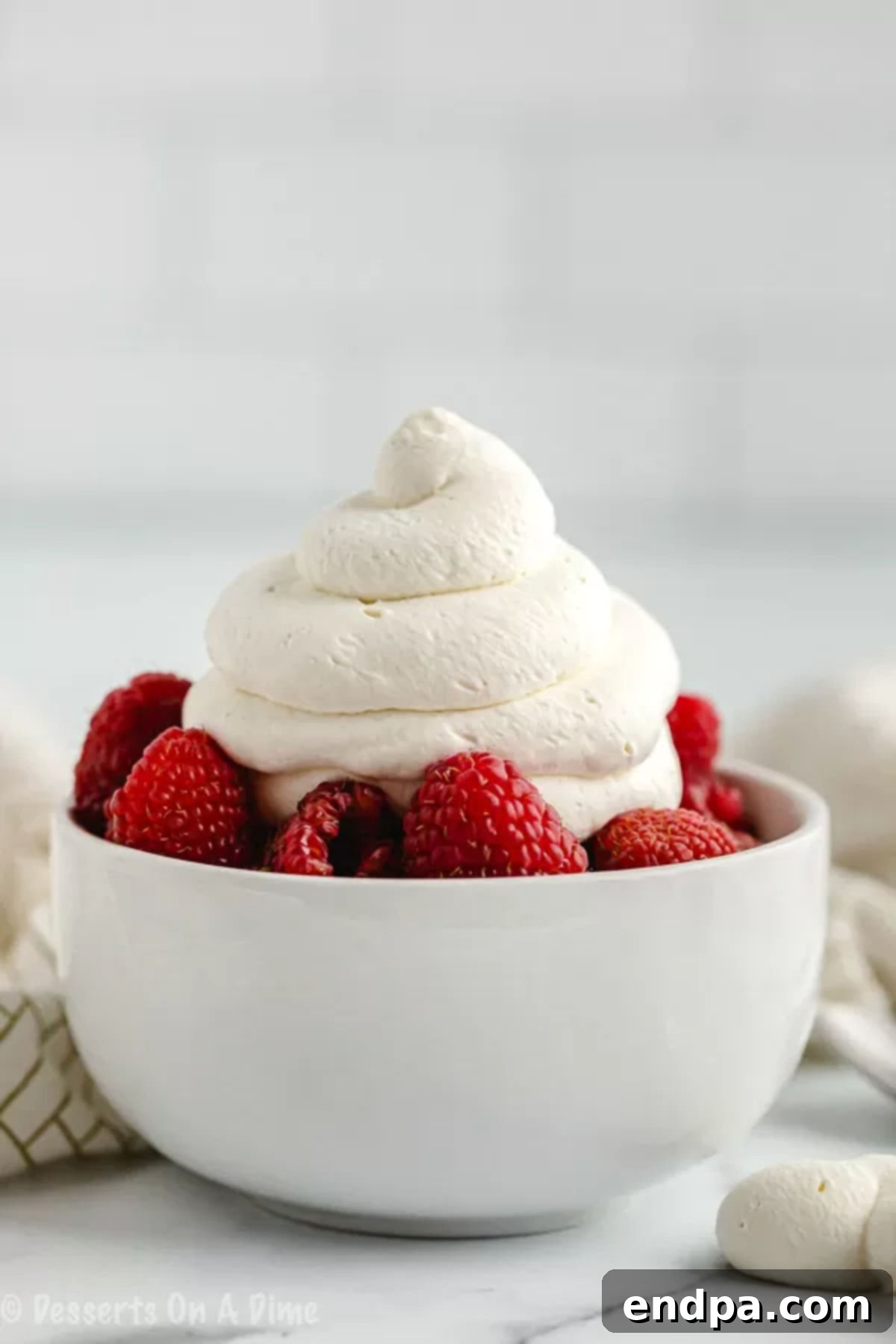 Bowl of fresh mixed berries generously topped with fluffy homemade keto whipped cream.