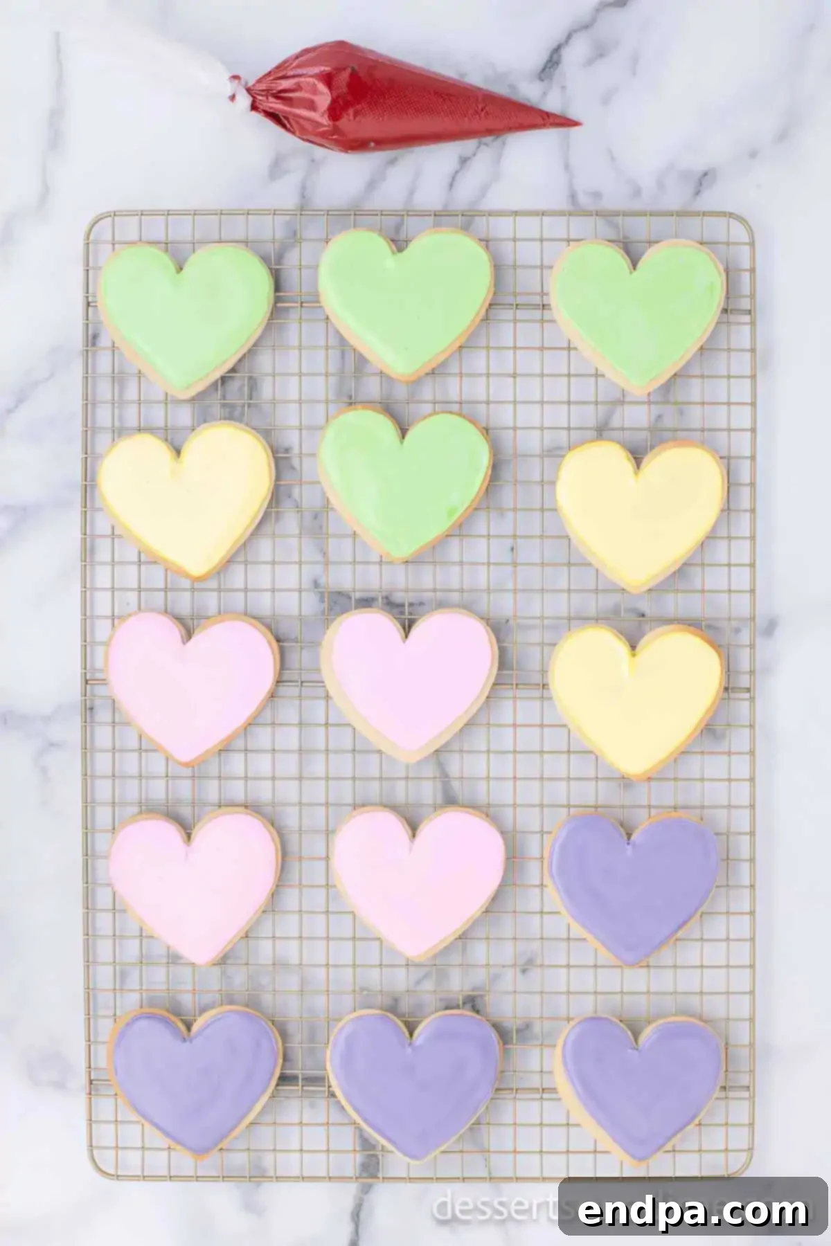 Plain heart-shaped cookies cooling on a wire rack, awaiting their royal icing decoration.