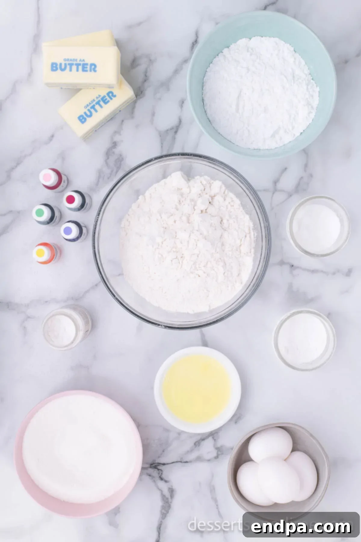 A flat lay image displaying key ingredients for sugar cookies: flour, baking powder, eggs, powdered sugar, and various gel food colorings.