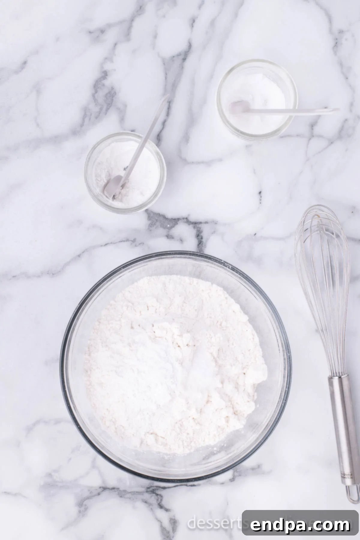A bowl containing flour, baking powder, and salt, shown after being sifted together.
